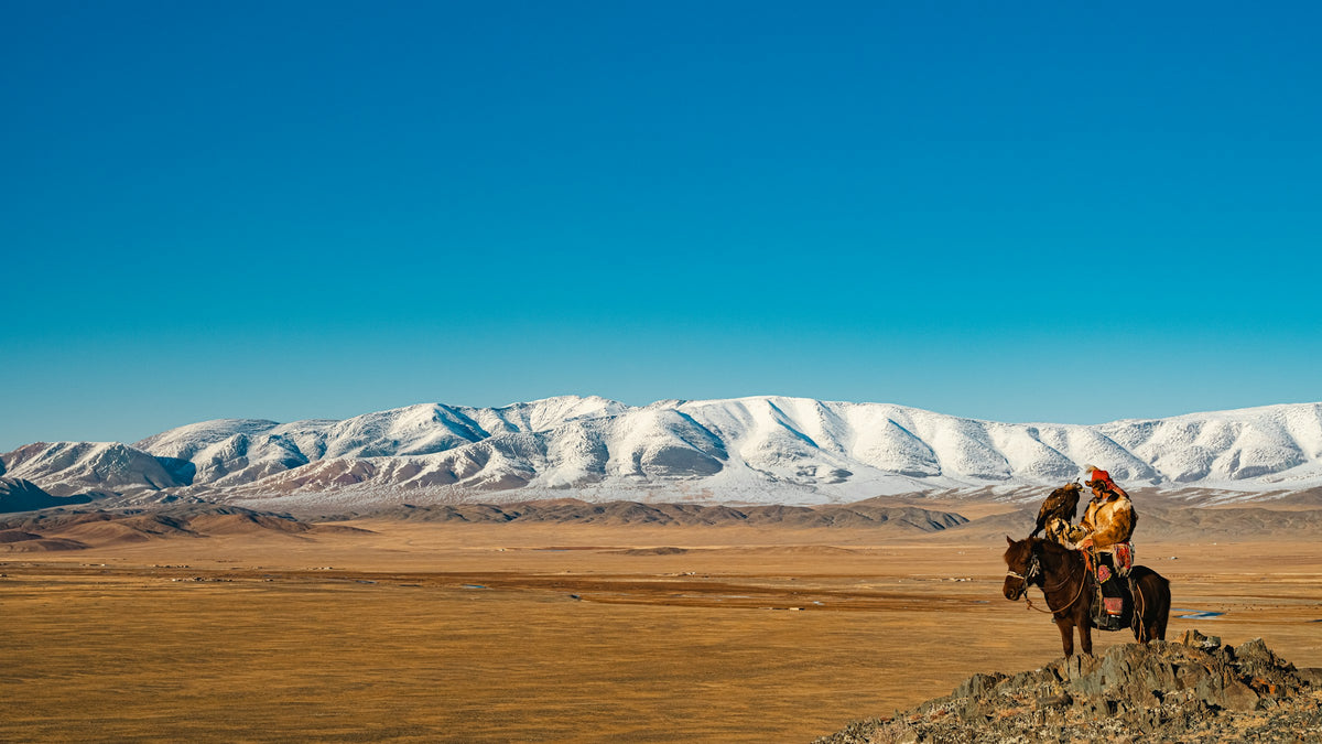 A rider overlooks snowy Mongolian mountains