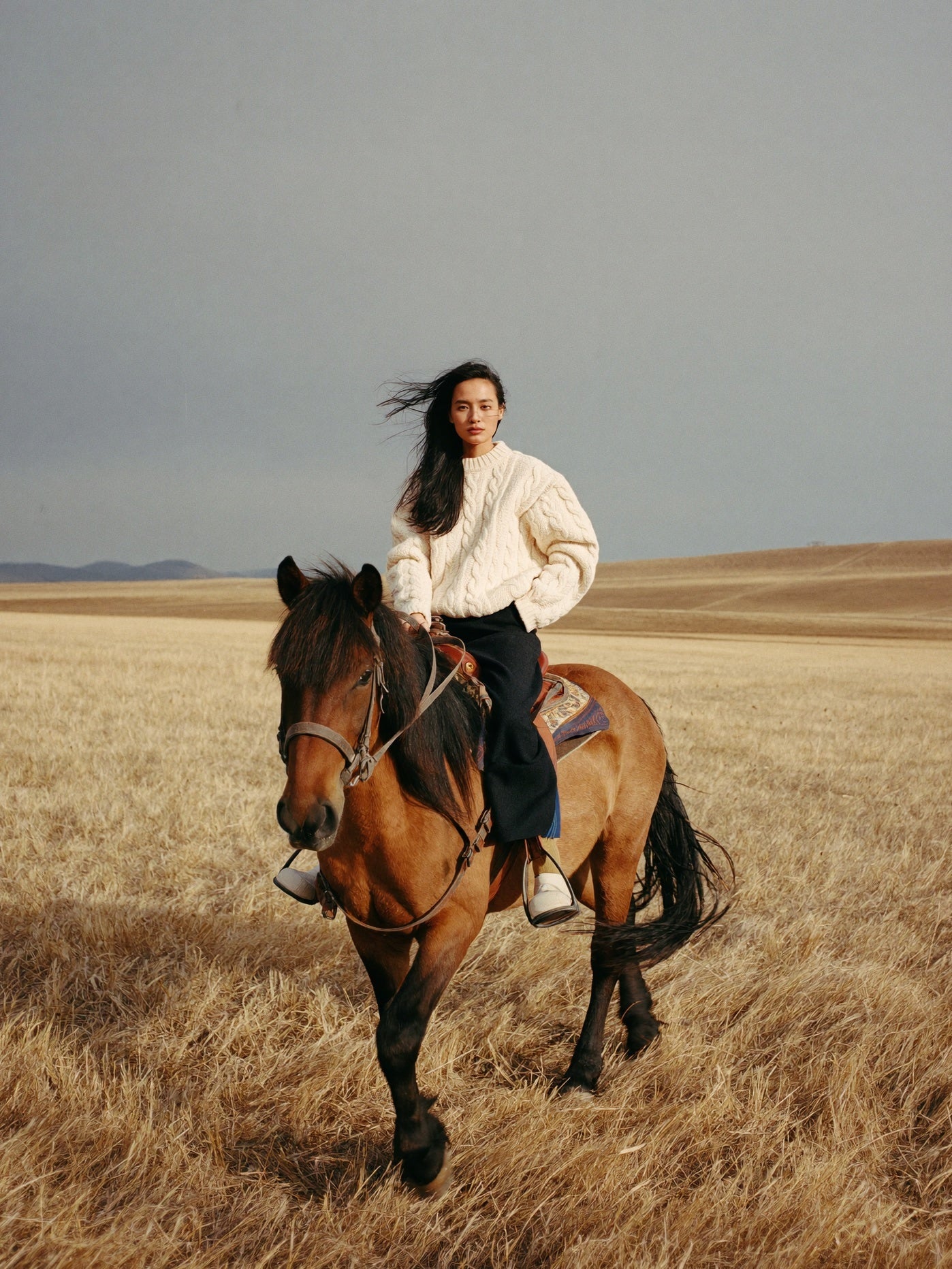 Rider in cream cable knit on a Mongolian horse