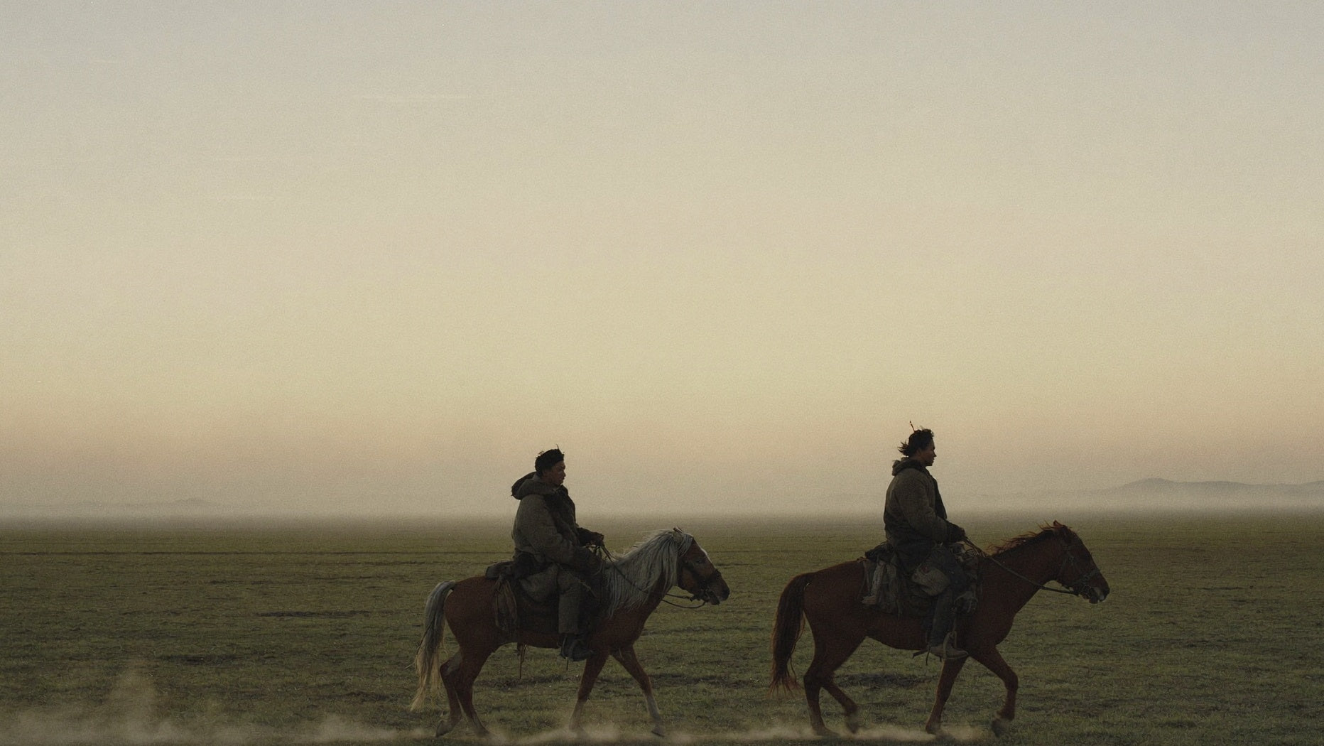 Two riders at dawn on the Mongolian steppe
